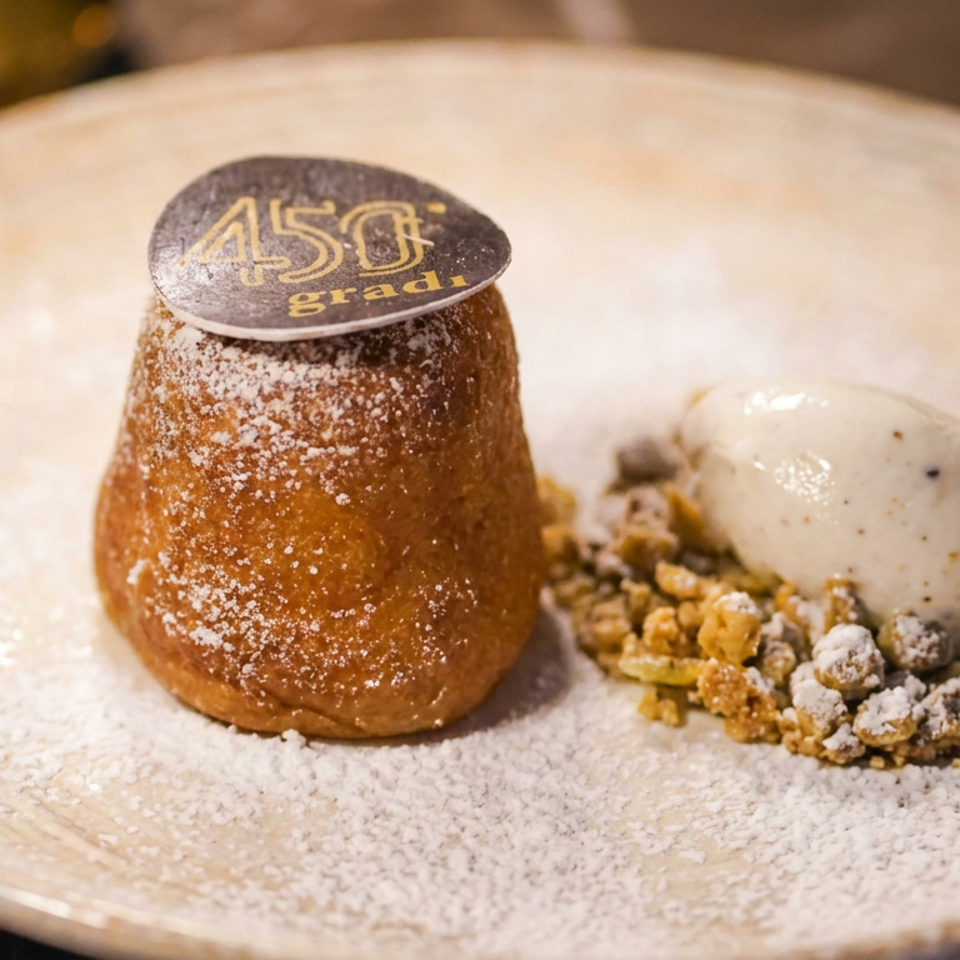 Pistachio-dusted dessert with vanilla ice cream, crunchy crumble, and powdered sugar on a ceramic plate.